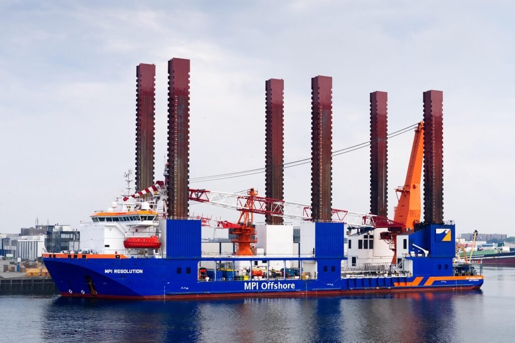 Operador de guindaste offshore movimentando contêiner entre barco de apoio e plataforma