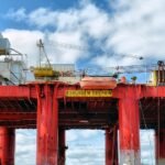 Técnico de segurança offshore inspecionando o convés de uma plataforma de petróleo ao amanhecer