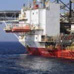 Grupo de colegas de embarque conversando no convés de uma plataforma de petróleo ao amanhecer